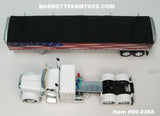 Item #69-2368 White Peterbilt 389 48-inch Flattop Sleeper with American Flag High Sided Black Tarp Silver Frame Tandem Axle Wilson Pacesetter 43-foot Hopper Bottom Grain Trailer - USA 250 Year Anniversary Edition - 1/64 Scale – DCP by First Gear